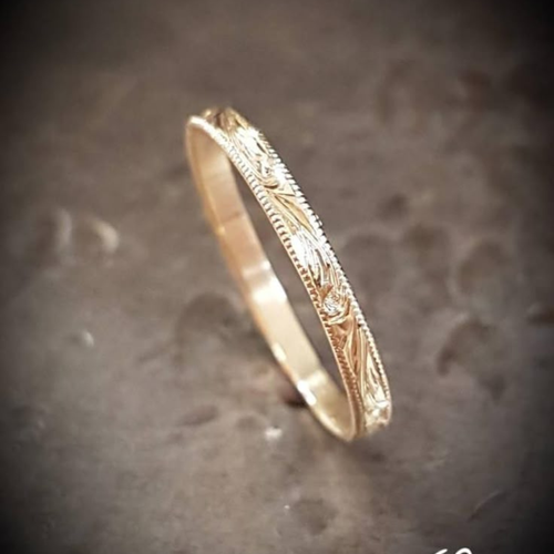 Gold ring with intricate design on a textured gray background