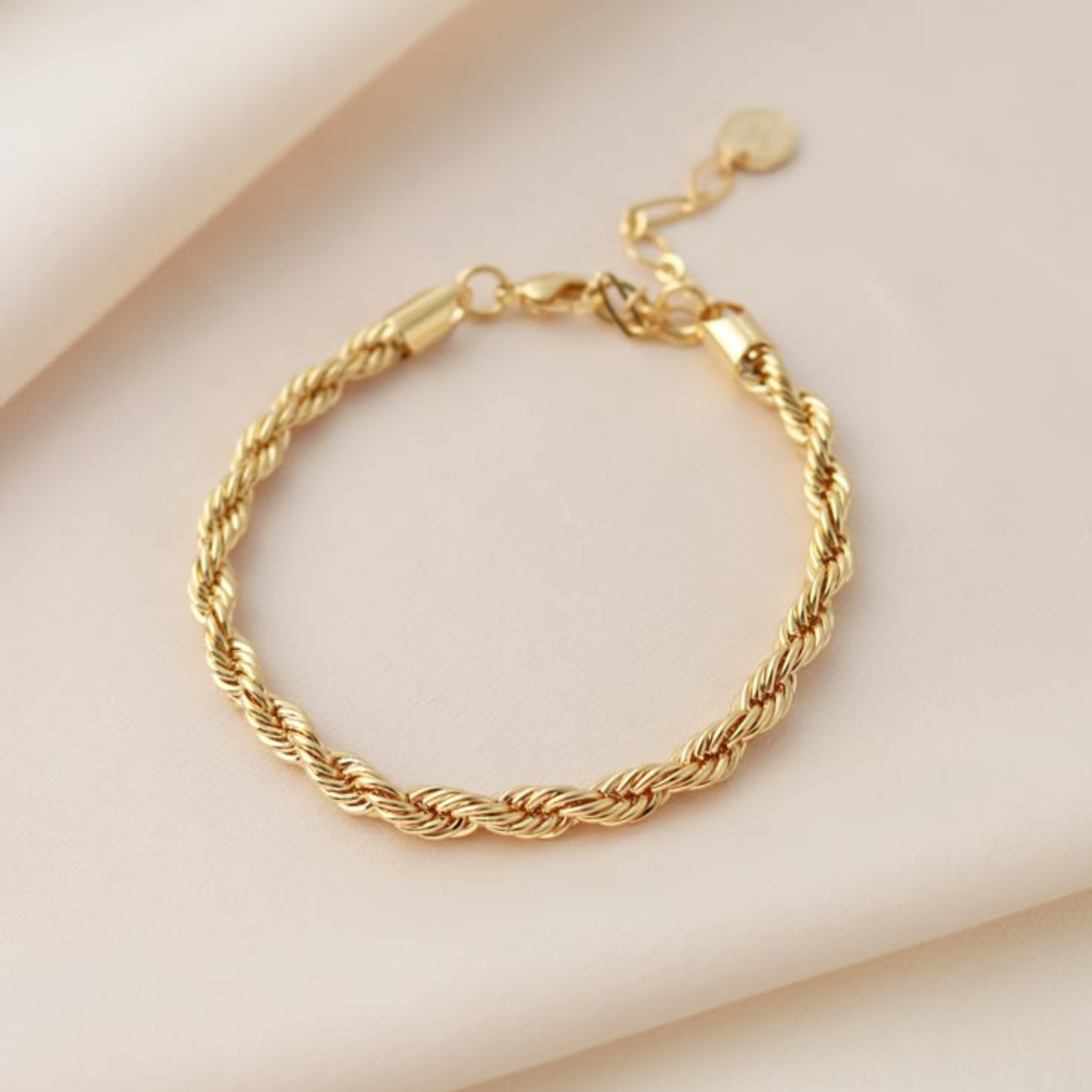 Gold braided bracelet on a light beige background