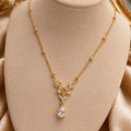 Gold necklace with a pendant on a beige mannequin bust