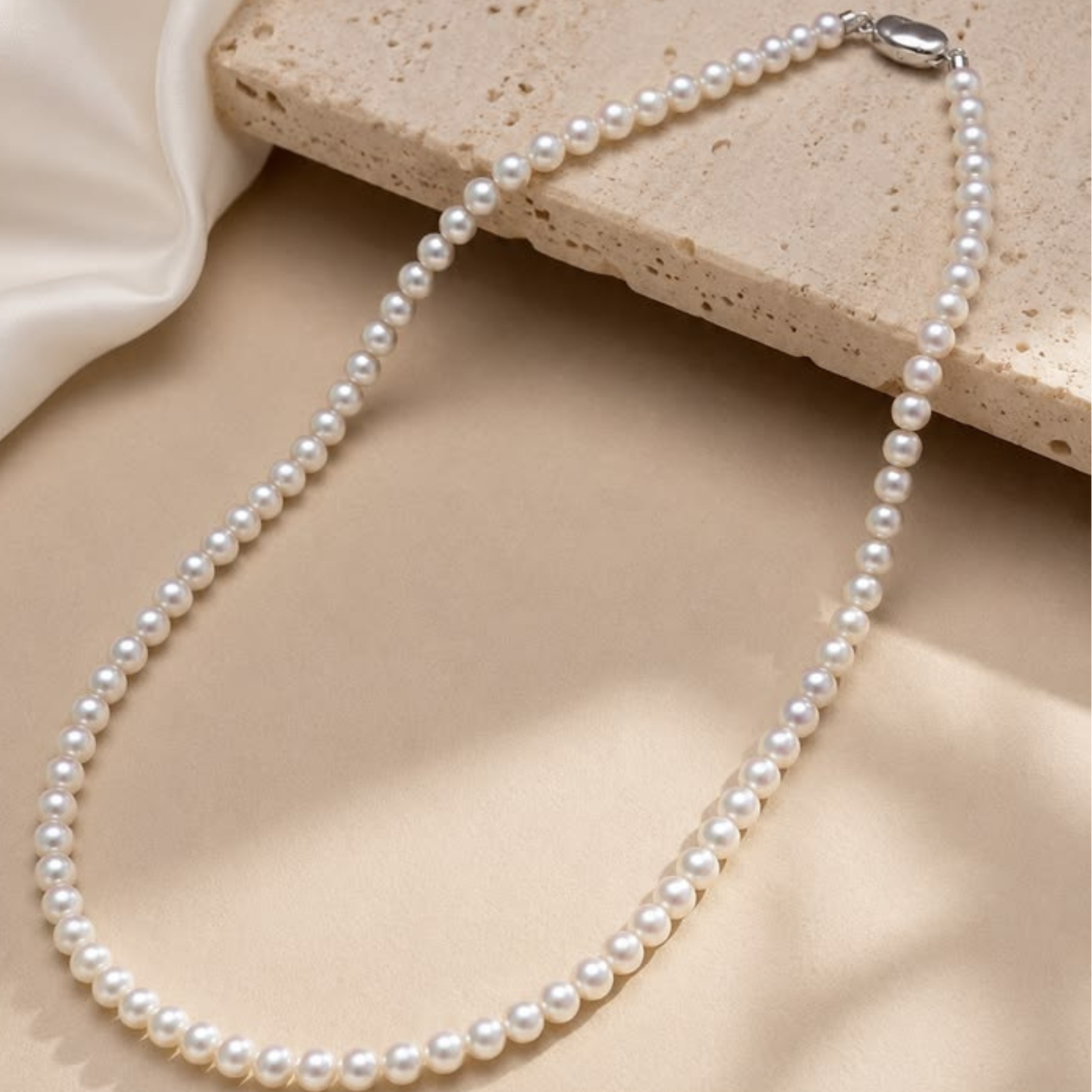Pearl necklace on a beige stone surface