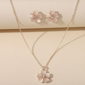 Flower-shaped necklace and earrings on a beige background