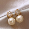Pearl earrings with gold and crystal accents on a satin surface