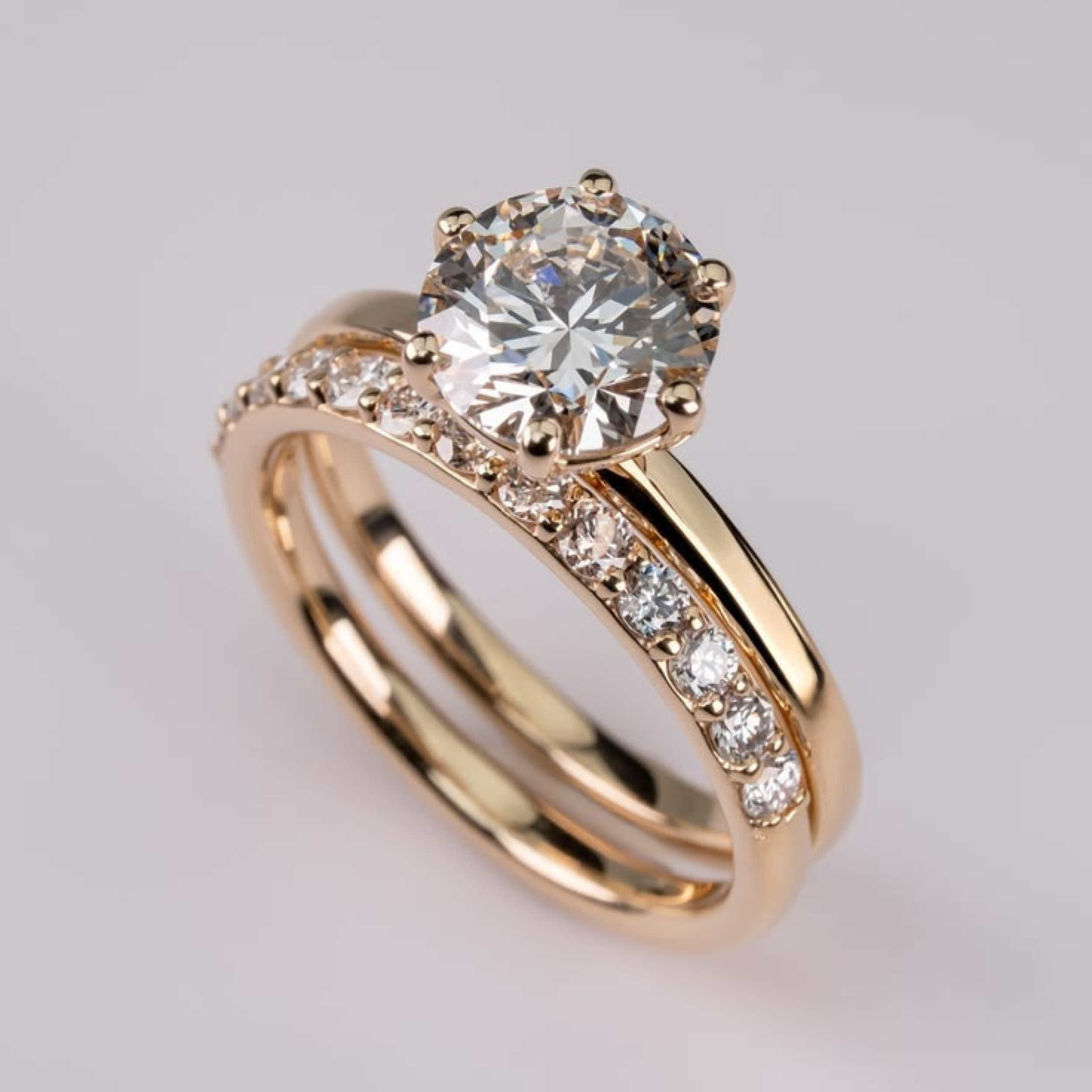 Gold ring with a large diamond and smaller diamonds on the band against a light gray background
